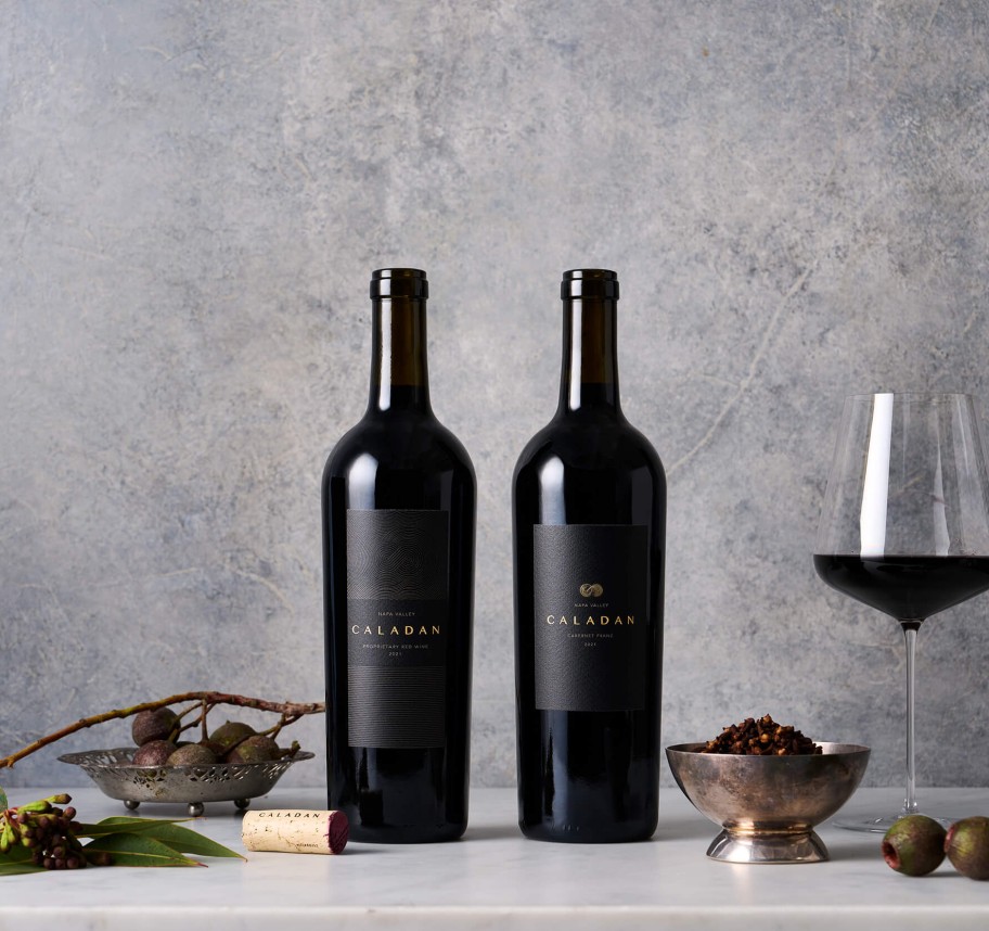 Two Bottles of Cardinale wine with a wine glass next to them 