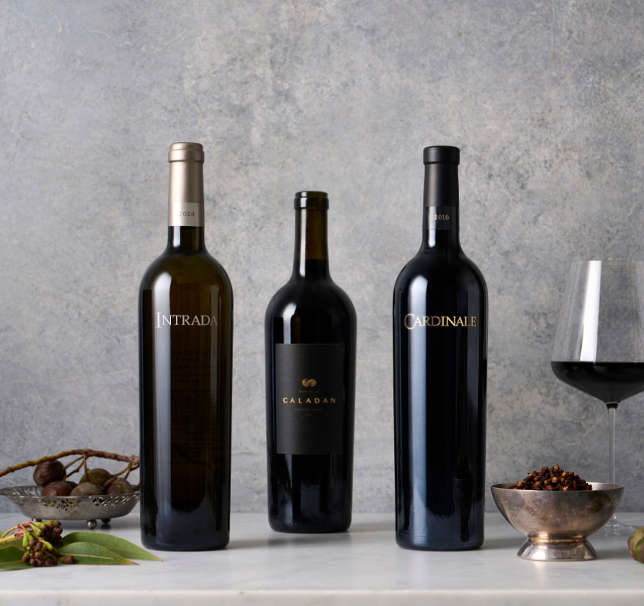 Three bottles of wine against a gray background